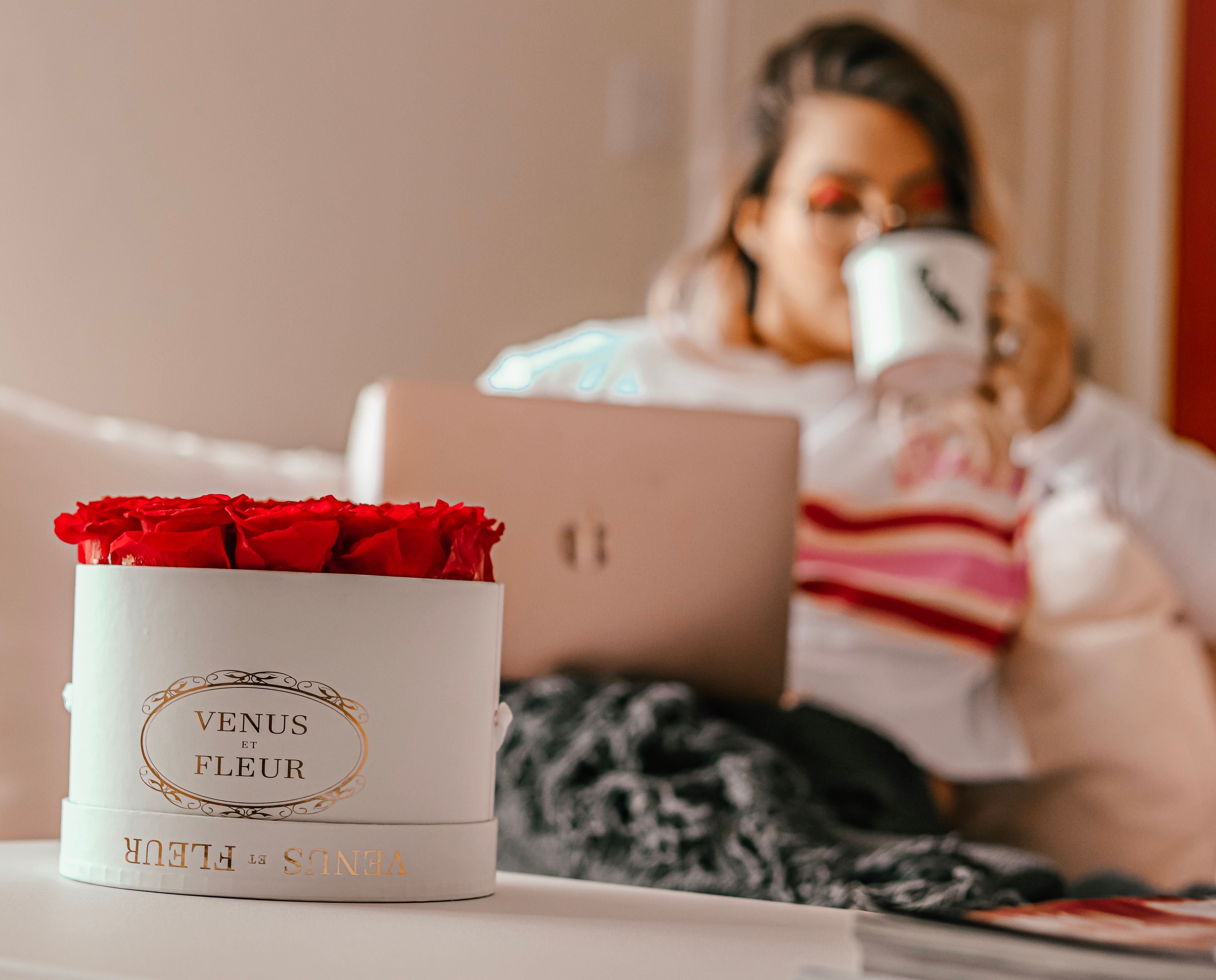 A woman sipping coffee by her small flower box arrangement of roses